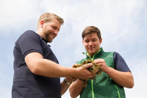 Two men holding silage